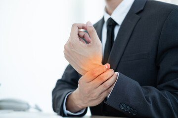 Businessman grasping the painful wrist caused by prolonged work on a laptop keyboard. Wrist numbness Arthritis While working at the office