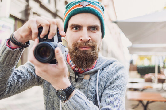 Young handsome man hipster takes images with retro styled camera. Hobby, leisure, lifestyle concept