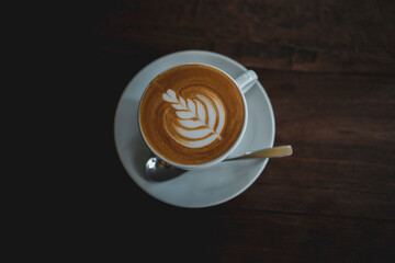 top view cup of coffee showing latte art on the dark brown wooden table
