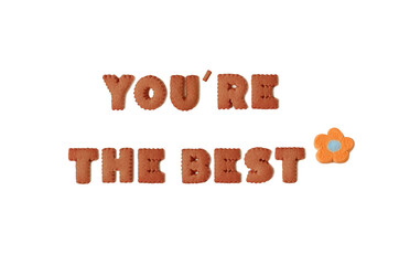 Text of YOU'RE THE BEST spelled with chocolate alphabet shaped cookies and orange marshmallow candy on white background