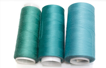sewing threads in turquoise shades on a white background