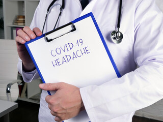 Medical concept about COVID-19 HEADACHE with phrase on the sheet.