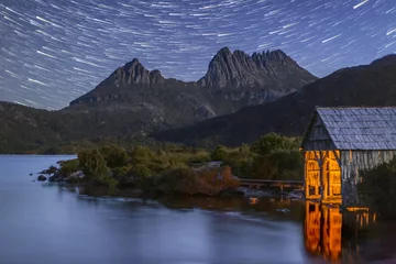 Crédence de cuisine en verre imprimé Mont Cradle Star trails over Cradle Mountain and the historic Dove Lake boat shed with the icon illuminated by candle light