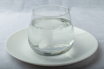 an effervescent medicine tablet dissolves in a glass of water