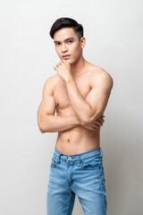 Muscular handsome shirtless Asian man posing in light gray studio isolated background