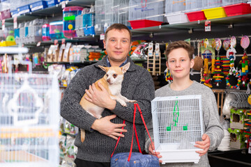 Happy man with teenager son and little dog buying pet supplies. High quality photo