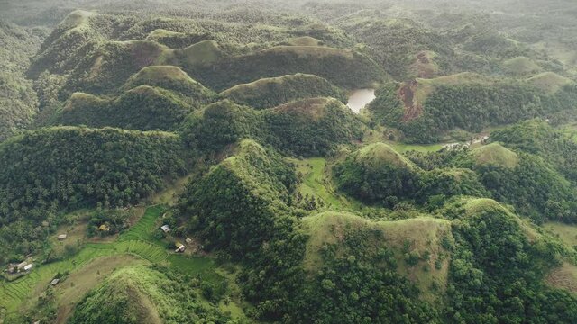 Top-down mountain lake aerial: green grass hills at Philippines countryside. Majestic Asia narure scape in soft light tones. Cinematic wildlife asian scenery in footage drone shot