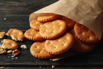 Paper bag with cracker biscuits on wooden background