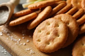 Board with tasty crackers and salt, close up