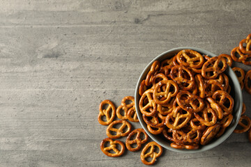 Obraz na płótnie Canvas Bowl with tasty cracker pretzels on gray table