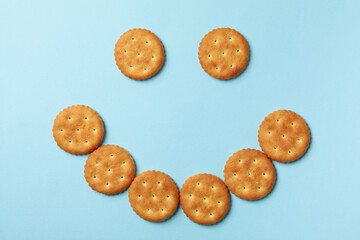 Smile face made of cracker biscuits on blue background