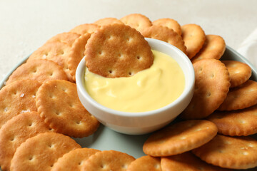 Napkin and plate with cracker biscuits and cheese sauce on white - light beige background