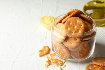 Glass jar with crackers, sauce and oil on white table