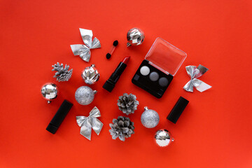 Christmas or new year flat lay of makeup products and decorations. Eyeshadow palette and lipstick on a red background