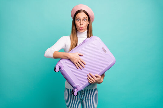 Photo of pretty speechless lady traveler hold violet suitcase airport registration overweight need pay wear specs pink beret white turtleneck striped jeans isolated teal color background