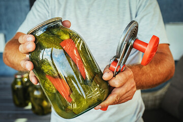 canning cucumbers, male hands holding a jar of cucumbers