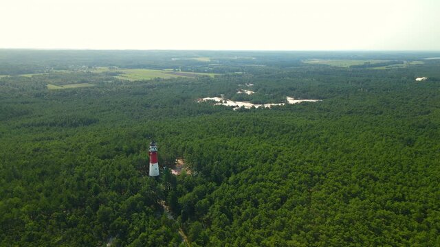 Stilo Lighthouse At Sasino Village Surrounded By Dense Thicket Lush Tree Forest In Osetnik, Poland. - Aerial Drone Shot