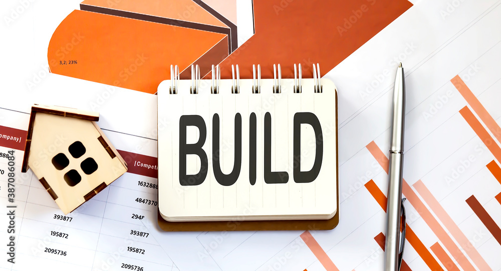 Poster BUILD text on notepad with paper sheet with pen and wooden house