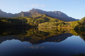 Fototapeta na wymiar A pond that reflects trees and mountains like a mirror. At dusk. Beautiful scenery of Japan.