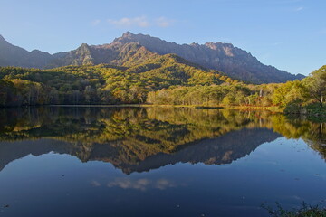 A pond that reflects trees and mountains like a mirror. At dusk. Beautiful scenery of Japan.