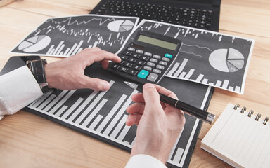 Fototapeta na wymiar Businessman using calculator. Working in financial graphs