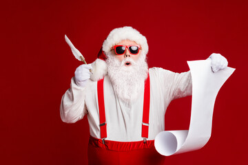 Portrait of his he attractive amazed stunned funny fat white-haired Santa writing wish present list...