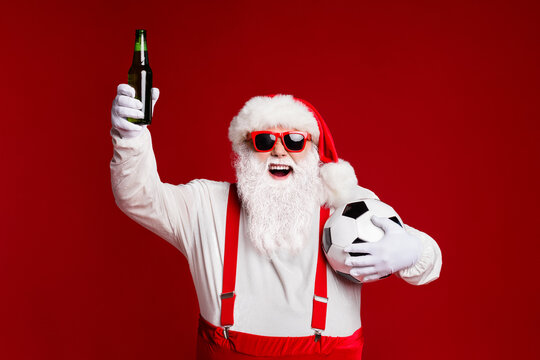 Portrait of his he attractive cheerful fat white-haired Santa drinking beer holding soccer ball having fun chill rest isolated bright vivid shine vibrant red burgundy maroon color background