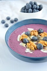 Acai smoothie bowl topping with walnut, coconut chips, chia seeds and blueberries. Selective focus
