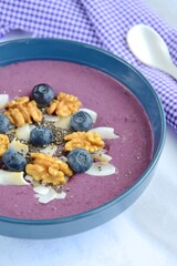 Acai smoothie bowl topping with walnut, coconut chips, chia seeds and blueberries