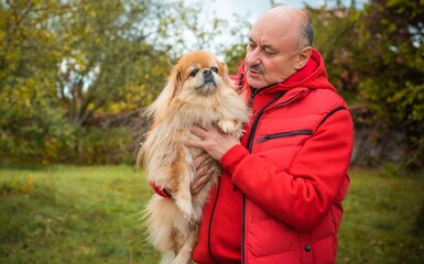 Senior man with a red little dog outdoor, man retired, lifestyle of older people