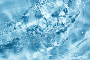 Splash of water flow with bubbles and ripples. Blue water texture. Selective focus