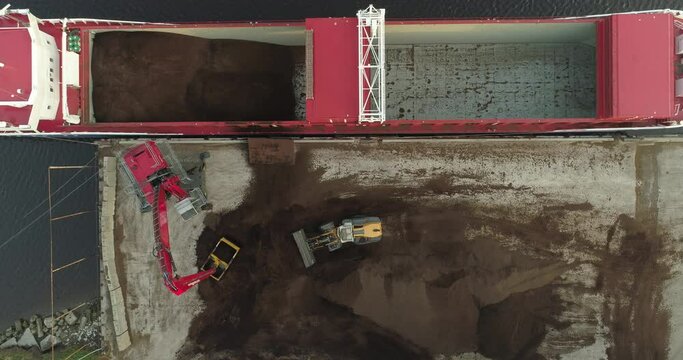 Cargo ship bulk carrier loading with peat soil top down aerial view