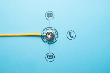 Stethoscope on table with phone, messenger and email contacts icons