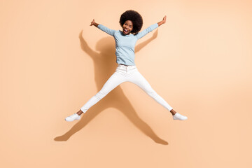 Fototapeta na wymiar Full length body size photo of curly funny girl with dark skin jumping pretending star isolated on beige color background