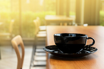 black coffee drink cup on wood table in café with morning sunlight