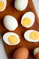 Hard Boiled Eggs on a rustic wooden board on a white wooden surface, top view. Flat lay, overhead, from above. Close-up.
