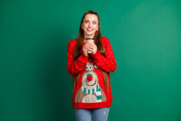 Photo of funny attractive lady hold hands hot coffee to go shop beverage look up empty space dreamer newyear mood atmosphere wear red ugly pullover isolated green color background
