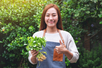 A young asian woman holding and making thumb up to show good sign to celery