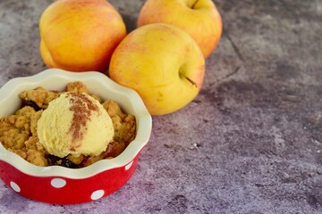 Apple crumble dessert with cinnamon and vanilla ice cream on dark background