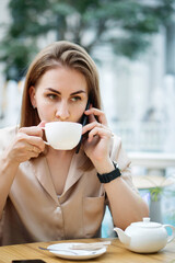 Businesswoman In Cafe Drinking Tea. Girl Listening Voice Message At Work