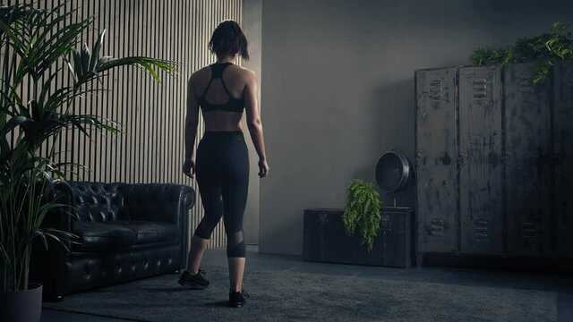 Young brunette fitness trainer preparing to workout in living room. Slow motion