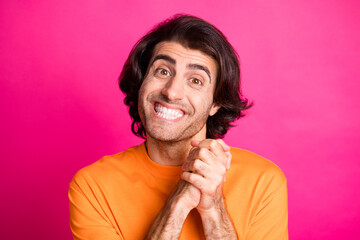 Photo of young guy toothy shiny smile hold hands look camera wear orange t-shirt isolated pink color background