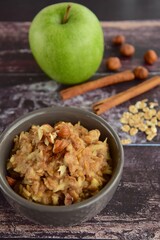 Breakfast oat porridge with apple, hazelnuts, honey and cinnamon powder  on a wooden rustic background.