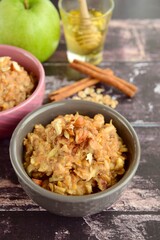 Hot breakfast oat porridge with apple, hazelnuts, honey and cinnamon powder  on a wooden rustic background.