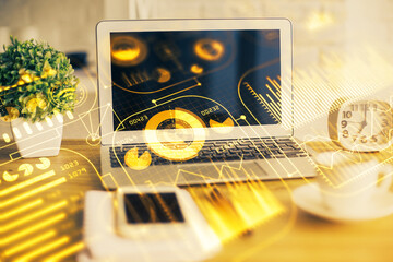 Computer on desktop in office with technology theme hologram. Double exposure. Tech concept.