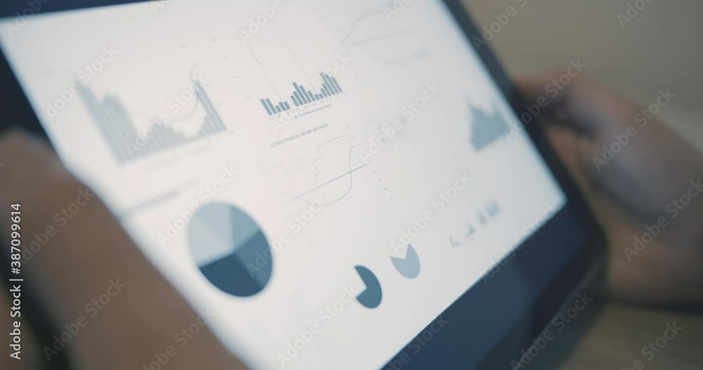 Poster close-up of business person using digital tablet with financial diagrams and graphs