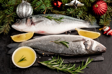 Raw sea bass fish with spices for the Christmas holiday on a stone background with a Christmas tree and new year toys