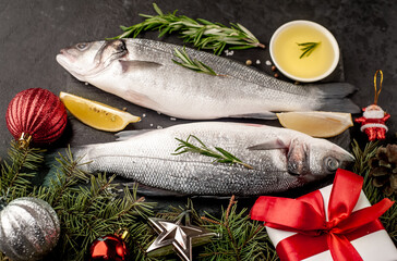 Raw sea bass fish with spices for the Christmas holiday on a stone background with a Christmas tree and new year toys