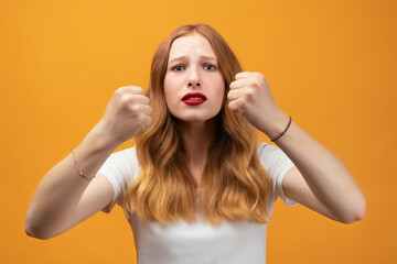 Pretty girl with wavy redhead, raising fists frustrated and furious