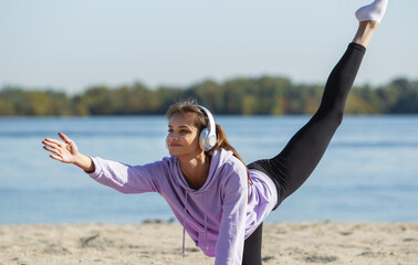 Energy. Young female athlete, woman training, practicing outdoors in autumn sunshine. Beautiful caucasian sportswoman doing yoga open-air. Concept of sport, healthy lifestyle, movement, activity.